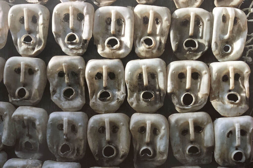 postcard front: empty plastic jugs squashed and turned on their sides to look like faces