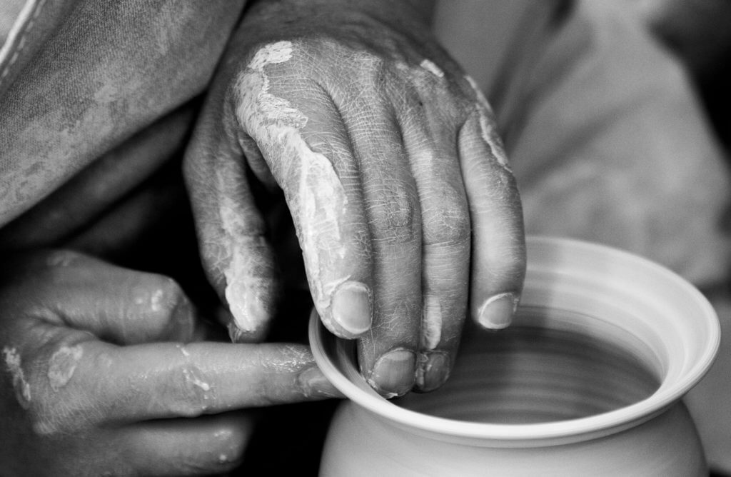 hands shaping a clay vessel on a potter's wheel